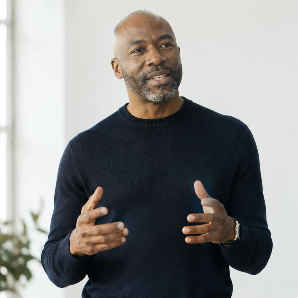 Middle-aged man practicing a confident speaking gesture in a bright studio